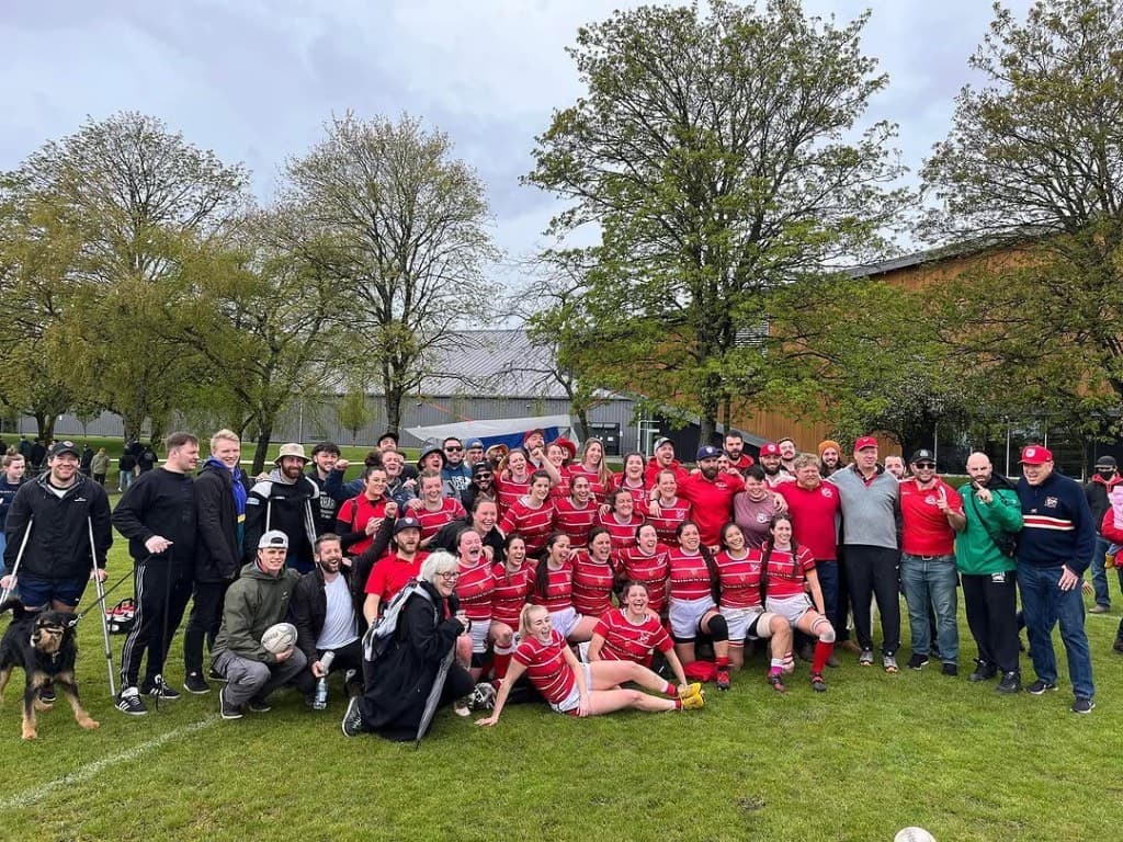 VRC Rugby women's team celebrating on the pitch with supporters, coaches and family after a BC Rugby match