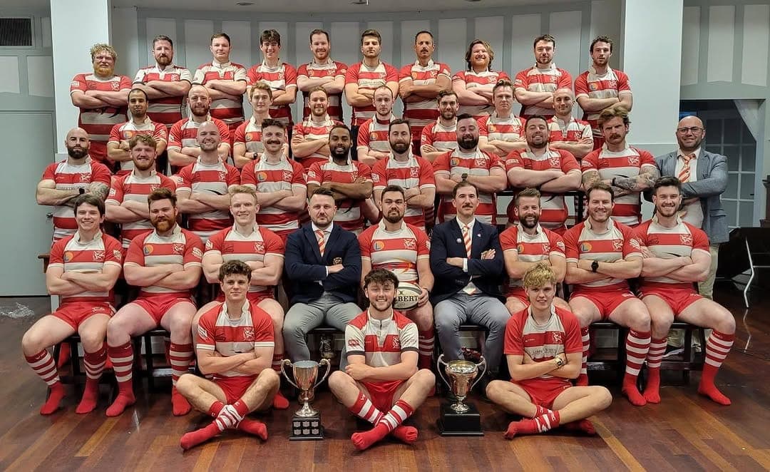 VRC Rugby men's senior side in a formal team portrait with BC Rugby trophies in the Vancouver Rowing Club clubhouse